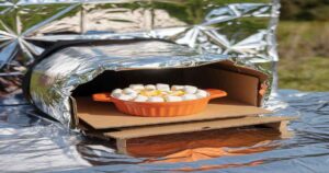 A solar oven made of reflective material cooking food using sunlight, demonstrating renewable energy.